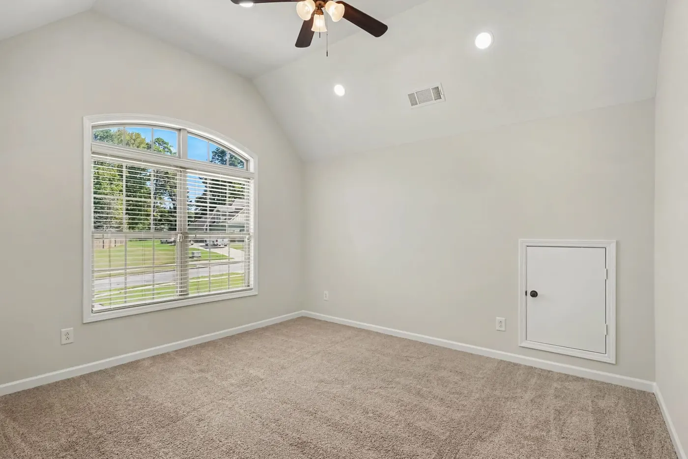 Bright, empty room with an arched window and fresh carpet