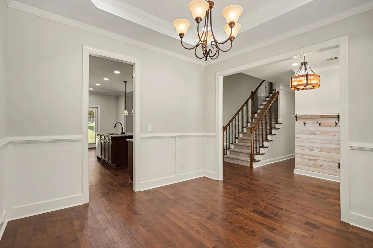 Dining room with a chandelier and hardwood floors, with the staircase beyond