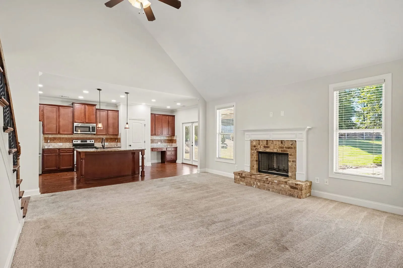 Open family room with a stone fireplace that flows into the kitchen