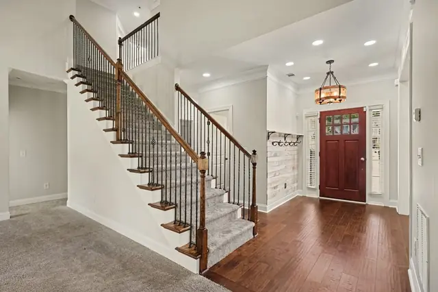 Foyer with an open staircase and hardwood floors