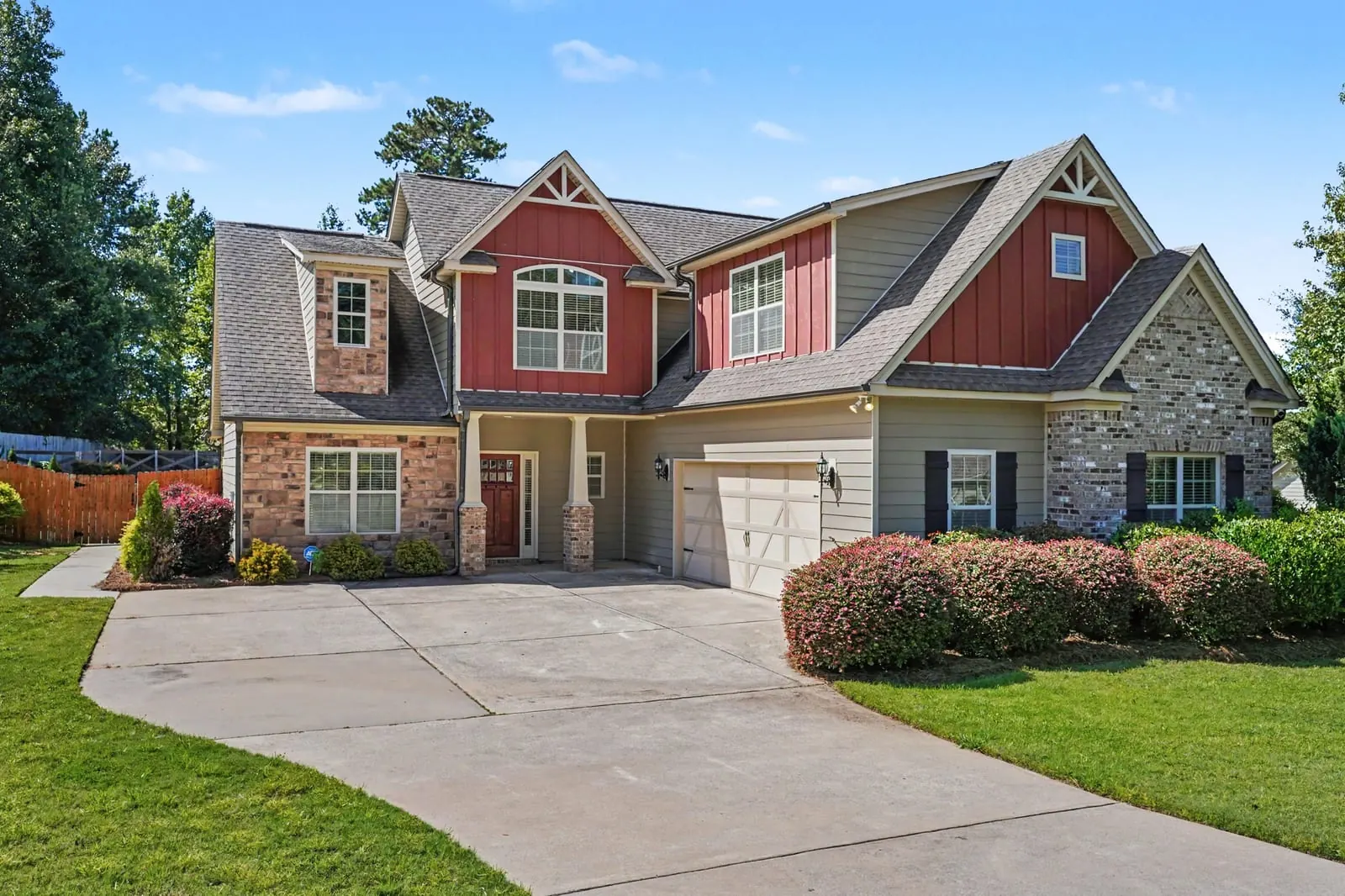 Two story craftsman style home with a stone and red siding front and a curved driveway at 139 Caraway Road