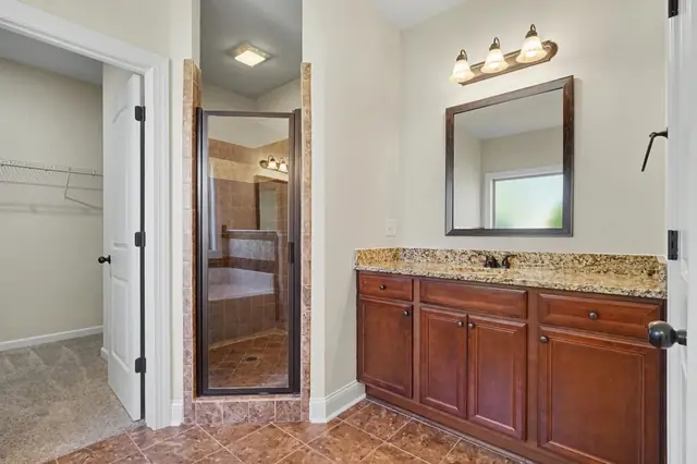Primary bath with a granite vanity and a glass enclosed shower