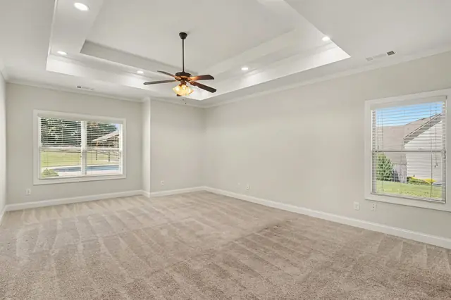 Primary suite with a tray ceiling and ceiling fan